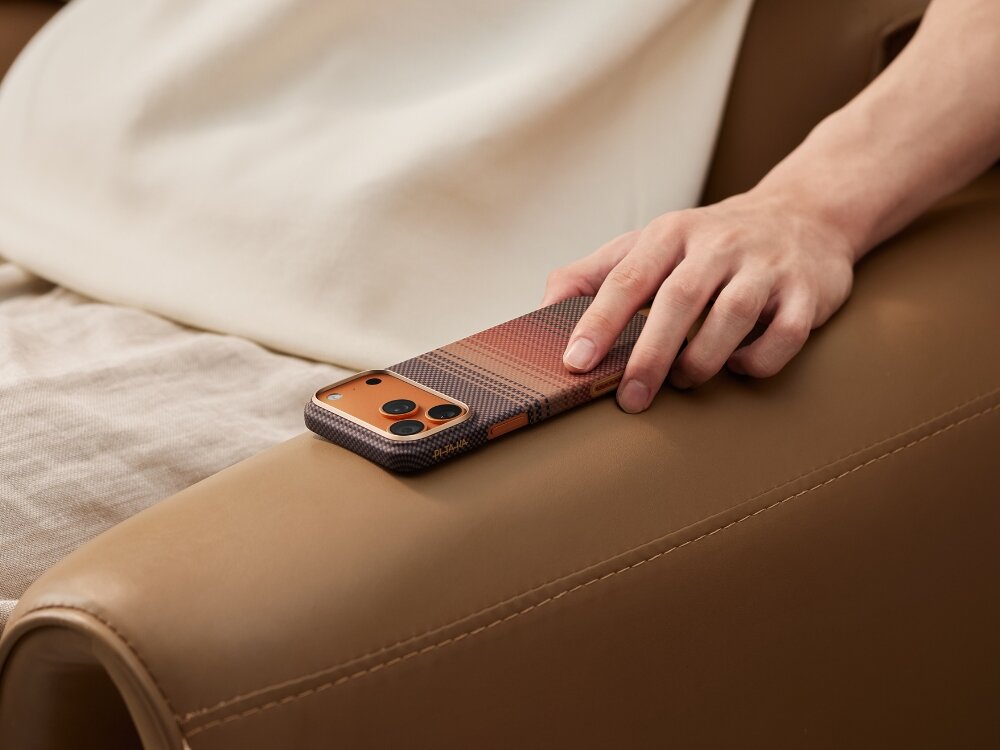 Etui PITAKA Ultra-Slim MagSafe
                telefon z etui trzymany w dłoni przy uchu na jasnym tle