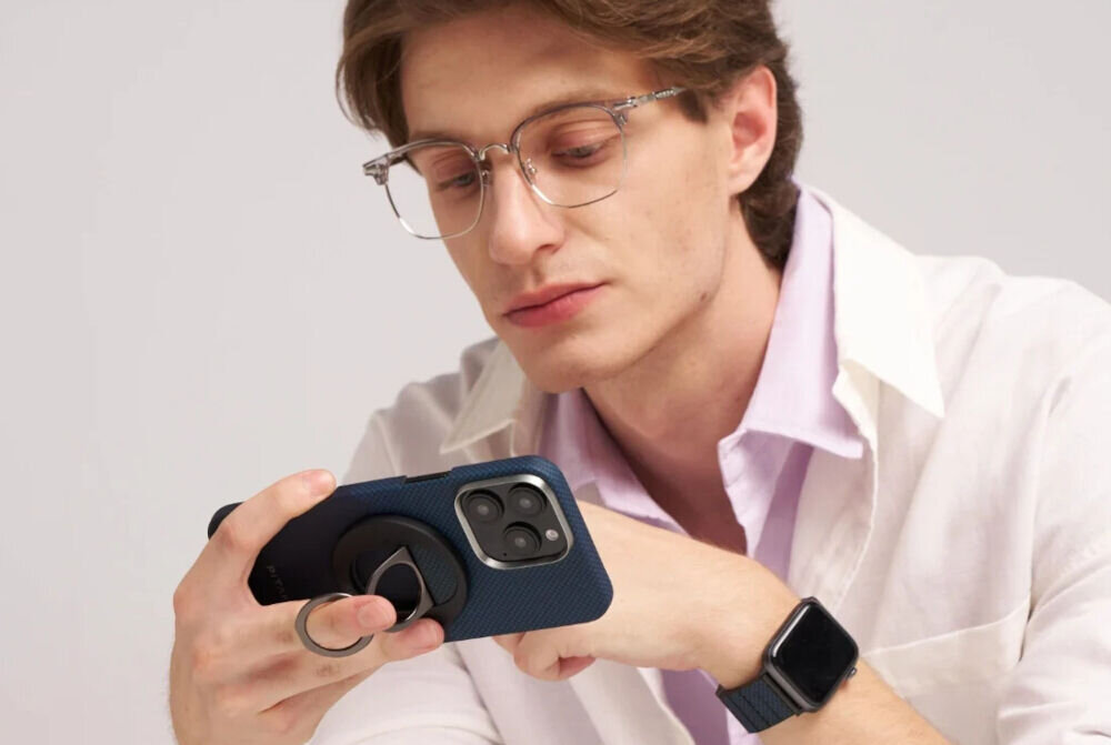 Uchwyt i podstawka PITAKA MagEZ Grip 3 MagSafe Czarno-szary mężczyzna trzymający telefon z przyczepionym uchwytem w dłoni jasne tło cienki uchwyt MagSafe z aramidu