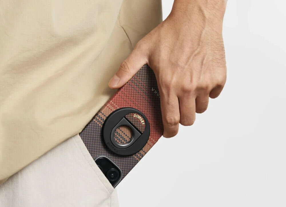 Uchwyt i podstawka PITAKA MagEZ Grip 3 MagSafe Czarno-brązowy telefon wyciągany ze spodni przez mężczyznę założony uchwyt jasne tło cienki uchwyt MagSafe z aramidu