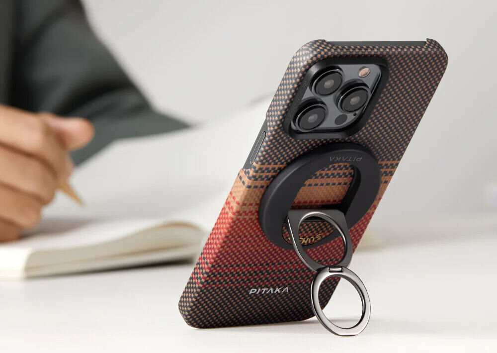 Uchwyt i podstawka PITAKA MagEZ Grip 3 MagSafe Czarno-brązowy prezentacja uchwytu przyczepionego do telefonu stojącego w pionie w tle osoba siedząca z zeszytem Kompatybilność MagSafe i MagEZ 2.0 – szybkie mocowanie magnetyczne silne magnesy