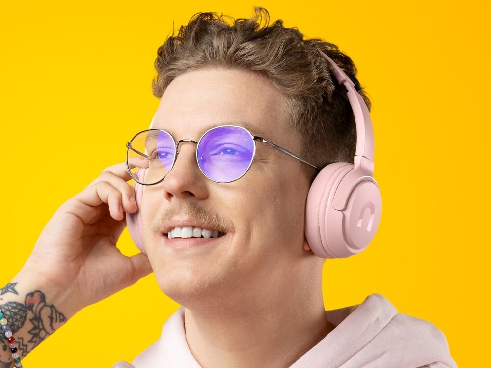 Słuchawki nauszne NICEBOY Hive Prodigy 4 50 godzin pracy bateria 380 mAh, osoba z założonymi słuchawkami nausznymi na żółtym tle