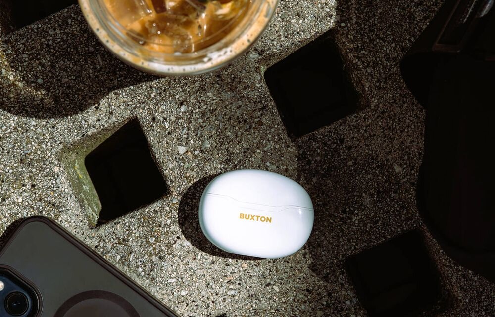 Słuchawki dokanałowe BUXTON BTW 7200 Tuya tryb gry niska latencja mikrofony HD sterowanie dotykowe Siri Google Assistant, etui ładujące leżące na betonowym stole