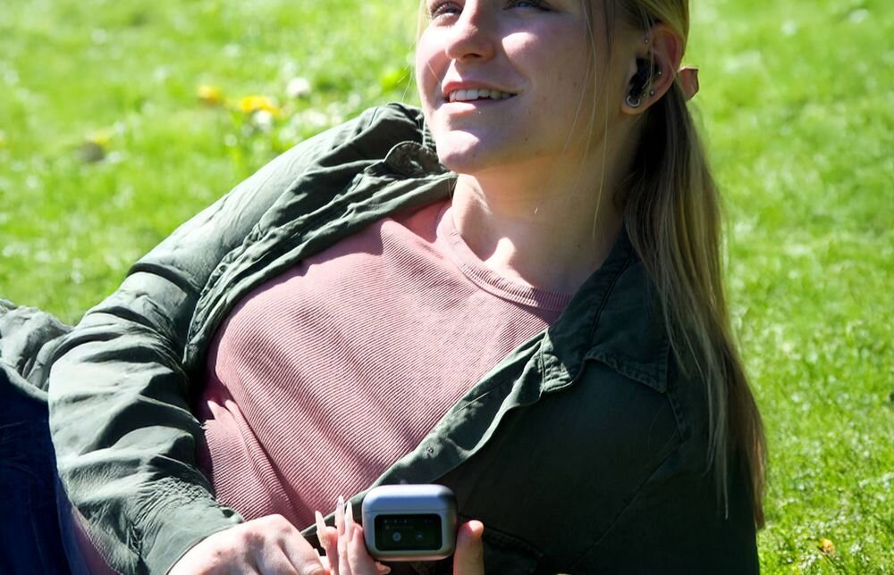 Słuchawki dokanałowe BUXTON BTW 9600 Wingate ANC z ANC 35 dB, ENC i etui Smart Case z wyświetlaczem, osoba z założonymi słuchawkami oraz z etui ładującym w ręku