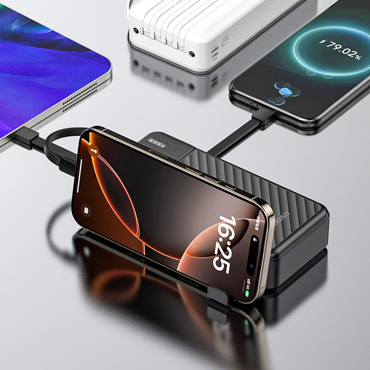 Na obrazie widać czarny powerbank z wbudowanymi kablami, do którego podłączone są dwa smartfony. Na ekranie jednego z telefonów widoczny jest czas 16:25 oraz wskaźnik ładowania 79.02%.