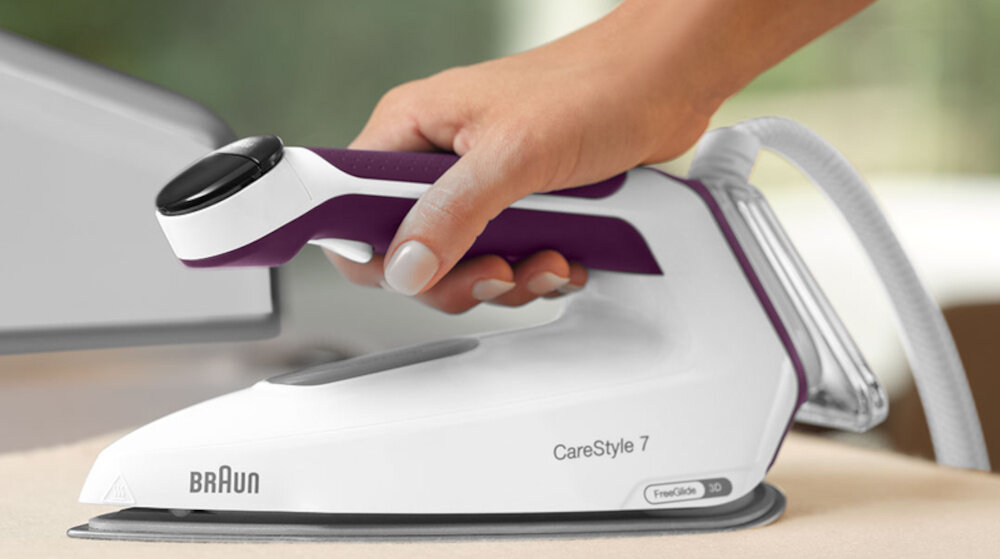 Osoba trzyma żelazko parowe z napisem \'BRAUN CareStyle 7\'.
