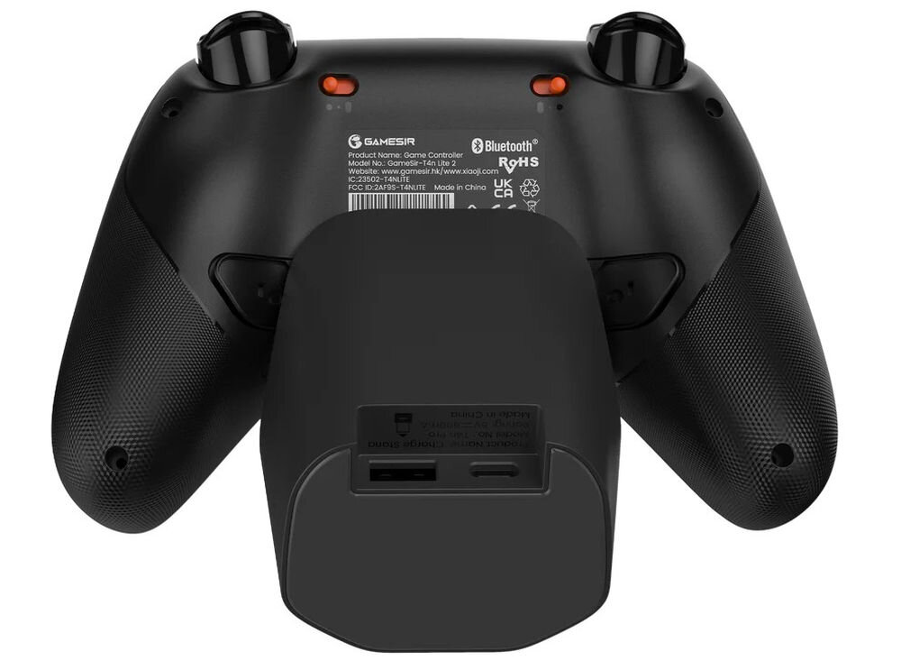 Czarny kontroler do gier z widocznymi przyciskami i tekstem: \'GAMESIR\', \'Bluetooth\', \'Model No: GAMESIR F9HS\'. W tle znajduje się czarna stacja dokująca z portami USB i USB-C.