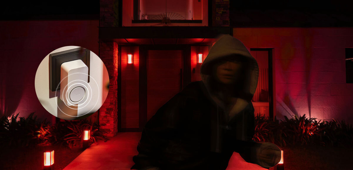 Dzwonek PHILIPS HUE, skutecznie, włączyć, ręcznie, hue, Zbliżenie na sygnalizator zamontowany na zewnątrz domu oświetlonego czerwonym światłem z rozmazaną sylwetką osoby w kapturze sugerującą włamanie.