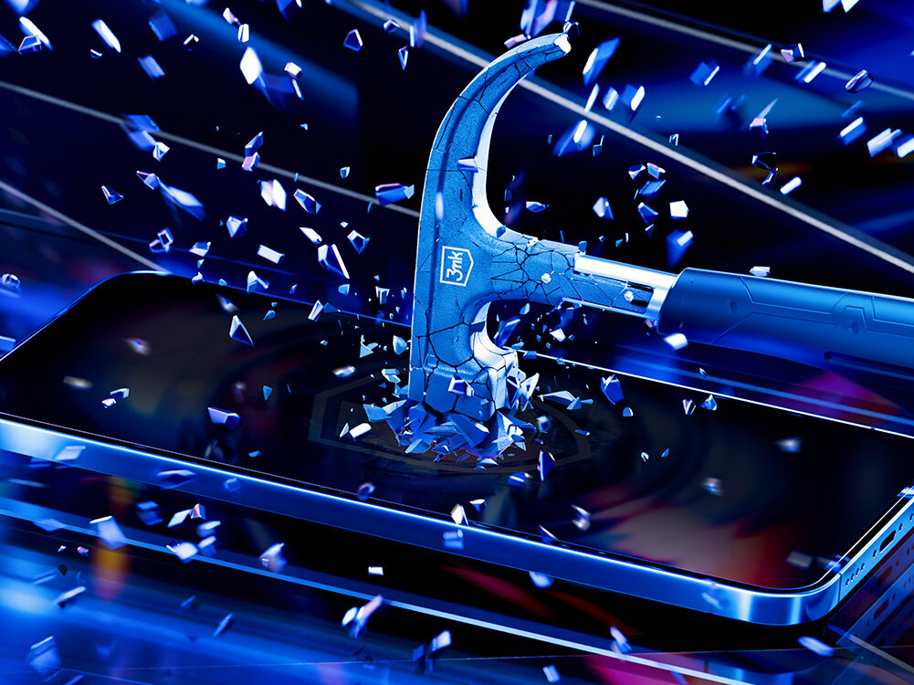 Na obrazie widać młotek uderzający w ekran telefonu, powodując rozprysk niebieskich odłamków szkła. Na młotku znajduje się logo z białym symbolem na niebieskim tle.