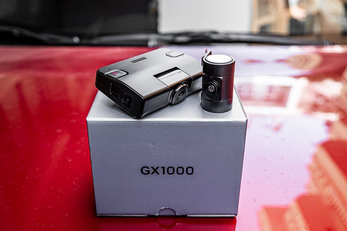 FINEVU GX1000 - Przednia i tylna kamera samochodowa ustawione na pudełku z napisem GX1000, w tle maska auta