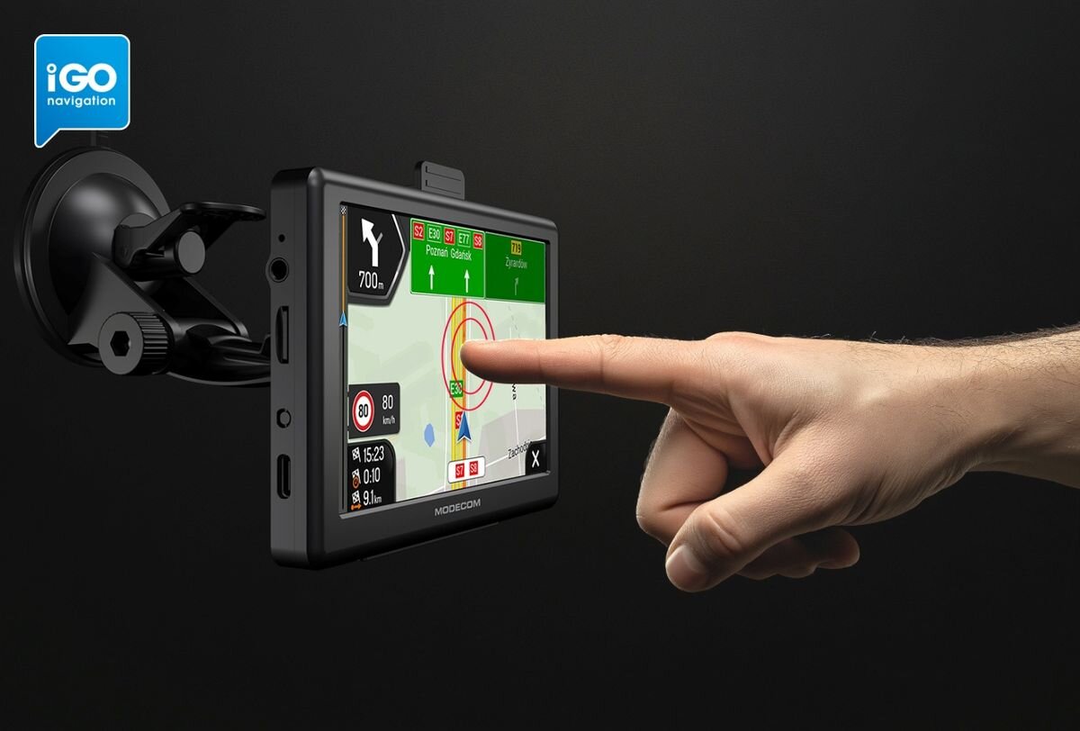Urządzenie nawigacyjne zamontowane na uchwycie, z wyświetlaczem pokazującym mapę i trasę. Logo \'iGO navigation\' widoczne w lewym górnym rogu.
