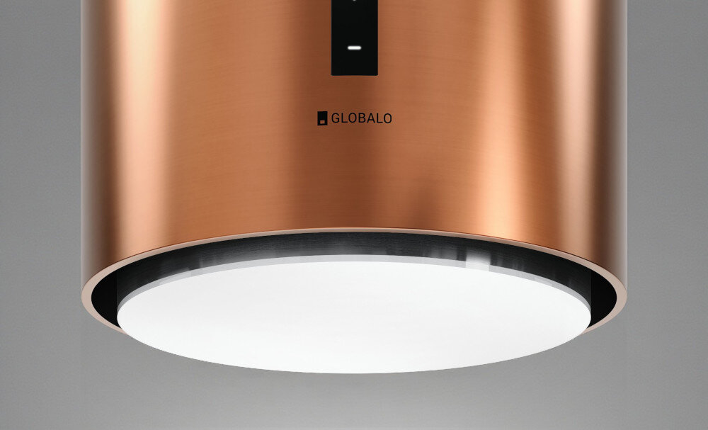 Okap GLOBALO Heweno Isola 39.2 Miedziany mat Zdjęcie przedstawia zbliżenie na dolną część cylindrycznego okapu kuchennego marki GLOBALO, z wyraźnie widocznym, okrągłym panelem LED odpowiadającym za równomierne, jasne oświetlenie powierzchni roboczej. Widoczny jest minimalistyczny design oraz dotykowy panel sterowania oświetlenie led naturalne światło komfort gotowania widoczność w kuchni gotowanie wieczorne energooszczędne oświetlenie led okap oświetlenie kuchenne