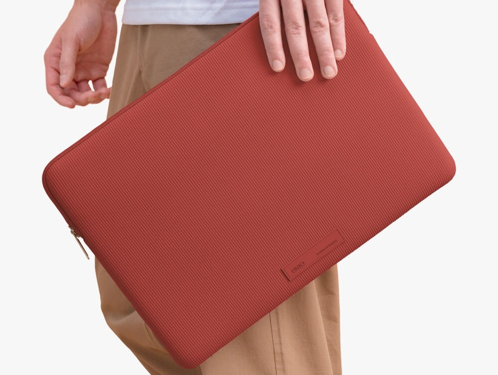Torba na laptopa UNIQ Cyprus Ridge Edition 14 cali Czerwony, elegancja, ochrona, opakowanie, bezpieczeństwo, osoba stoi bokiem trzymając w dłoni torbę na laptopa