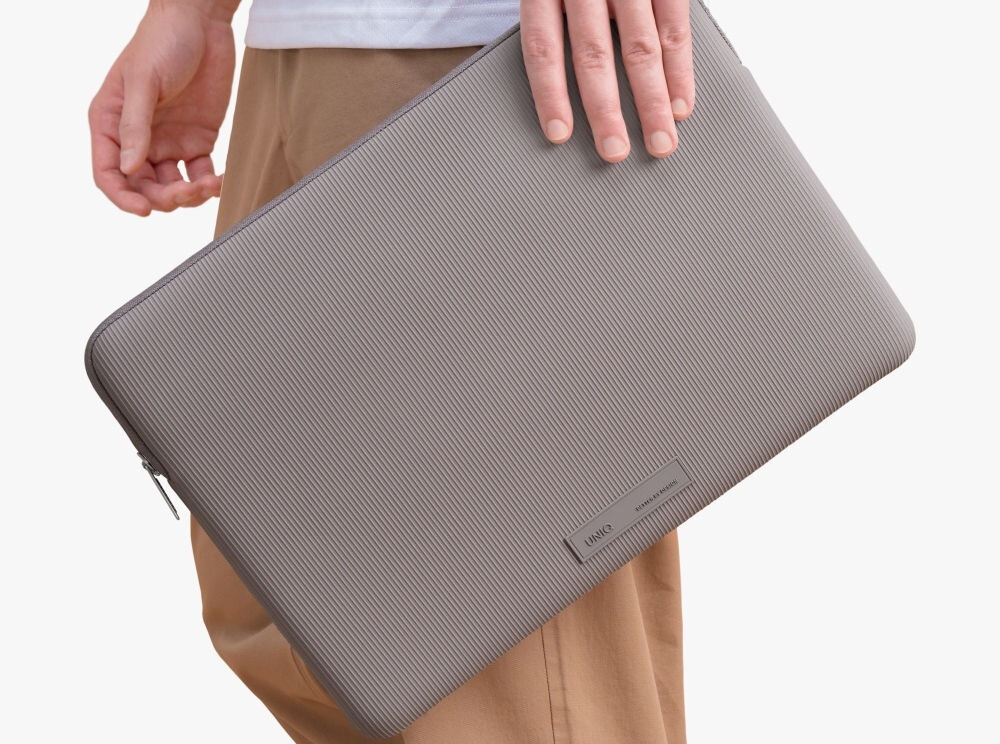 Torba na laptopa UNIQ Cyprus Ridge Edition 14 cali Szary, elegancja, ochrona, opakowanie, bezpieczeństwo, osoba stoi bokiem trzymając w dłoni torbę na laptopa