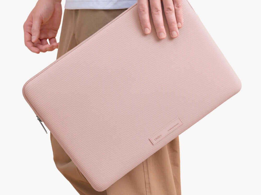 Torba na laptopa UNIQ Cyprus Ridge Edition 14 cali Różowy, elegancja, ochrona, opakowanie, bezpieczeństwo, osoba stoi bokiem trzymając w dłoni torbę na laptopa