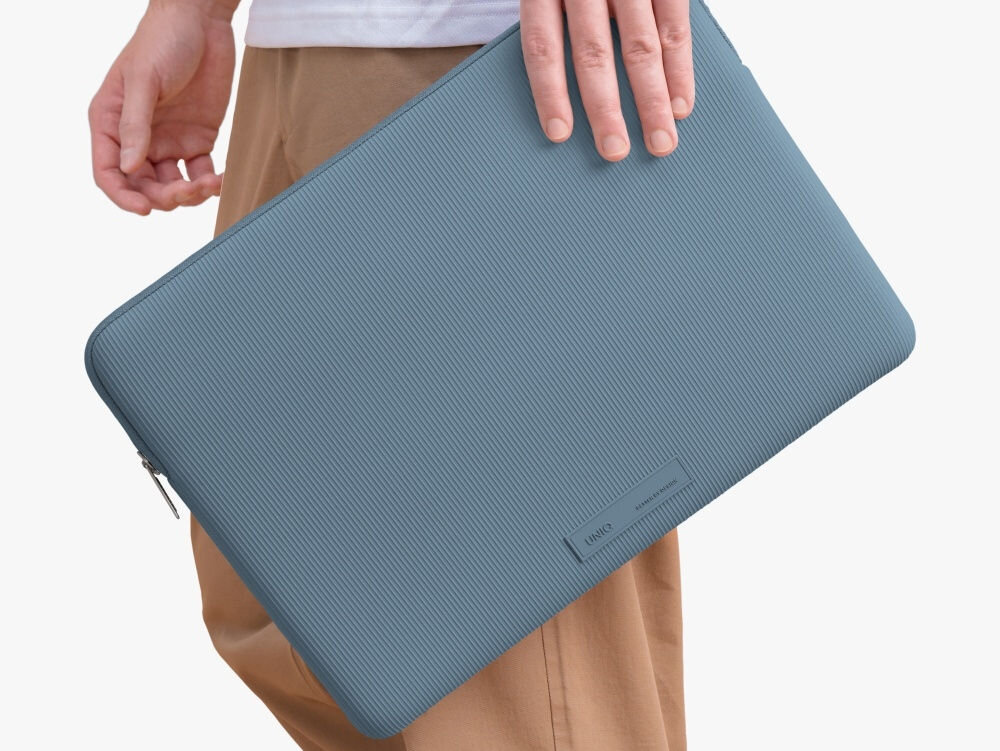 Torba na laptopa UNIQ Cyprus Ridge Edition 16 cali Niebieski, elegancja, ochrona, opakowanie, bezpieczeństwo, osoba stoi bokiem trzymając w dłoni torbę na laptopa