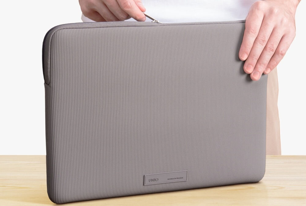 Torba na laptopa UNIQ Cyprus Ridge Edition 16 cali Szary, bezpieczeństwo, styl, design, wygląd, osoba otwiera torbę rozsuwając zamek torby stojącej na drewnianym blacie