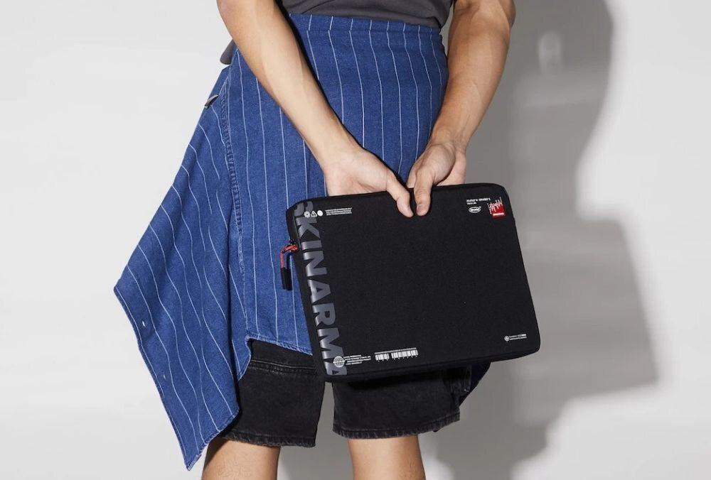 Torba na laptopa SKINARMA Fardel 14 cali Czarny etui trzymane przez mężczyznę w rękach na jasnym tle