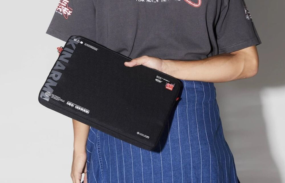 Torba na laptopa SKINARMA Fardel 14 cali Czarny prezentacja etui trzymanego w dłoni przez mężczyznę na jasnym tle elegancja praktyczność wyraziste logo podróż praca ochrona urządzenia