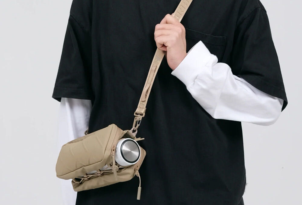 Torebka na telefon SKINARMA Juno Czarny zbliżenie na torebkę założoną na osobie szare tło crossbody z paskiem SCOUT+ i wodoodporną powłoką wygoda noszenia na co dzień do pracy w podróży