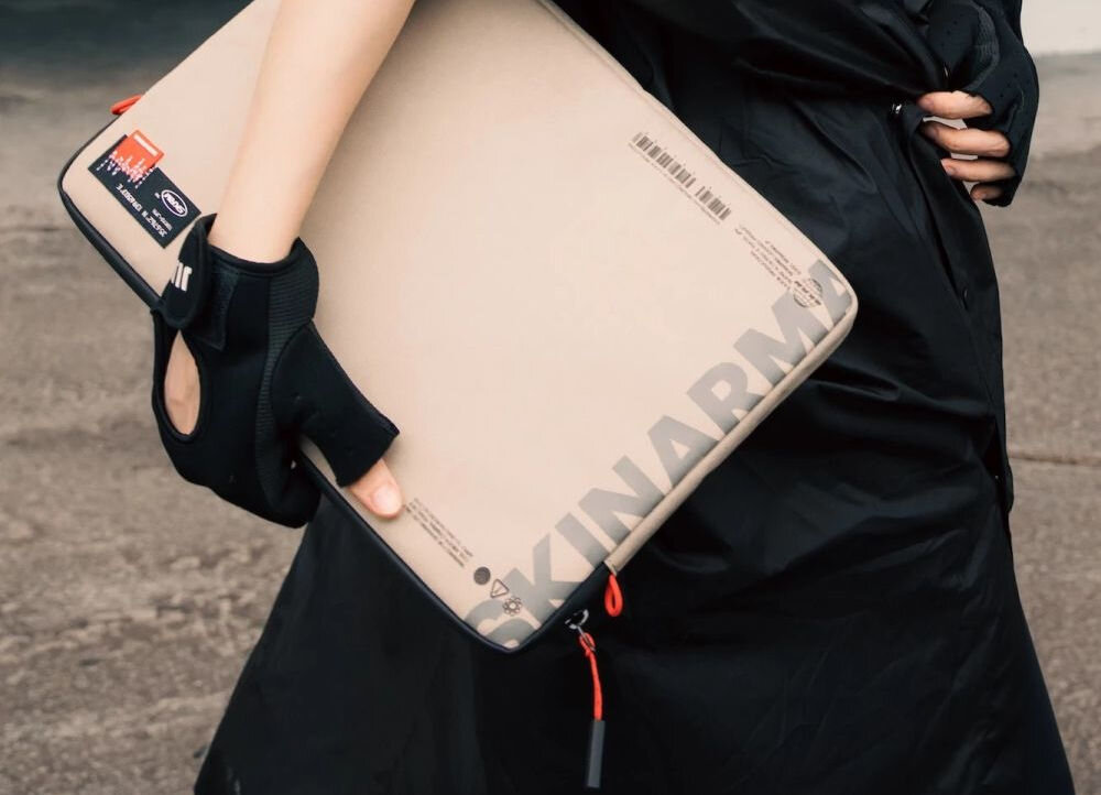 Torba na laptopa SKINARMA Fardel 14 cali Kość słoniowa zbliżenie na etui trzymane przez osobę