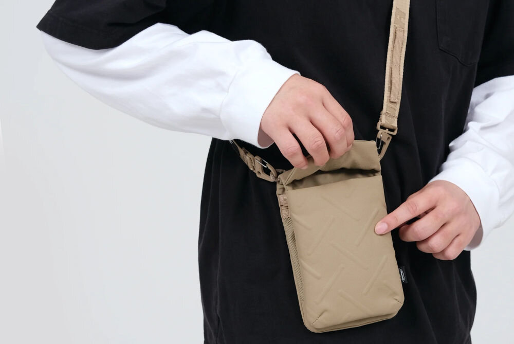 Torebka na telefon SKINARMA Juno Pomarańczowy zbliżenie na torebkę założoną na osobę jasne tło sling wodoodporny nylon składana konstrukcja design praktyczne rozwiązania spacer podróż