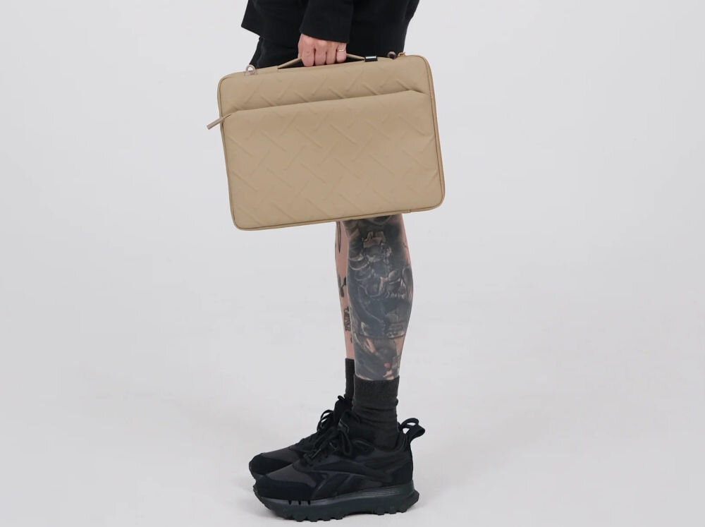 Torba na laptopa SKINARMA Juno 14 cali Zielony prezentacja torby trzymanej w dłoni osoba stojąca bokiem na szarym tle kieszenie, uchwyt boczny i funkcjonalny design ochrona przed wstrząsami