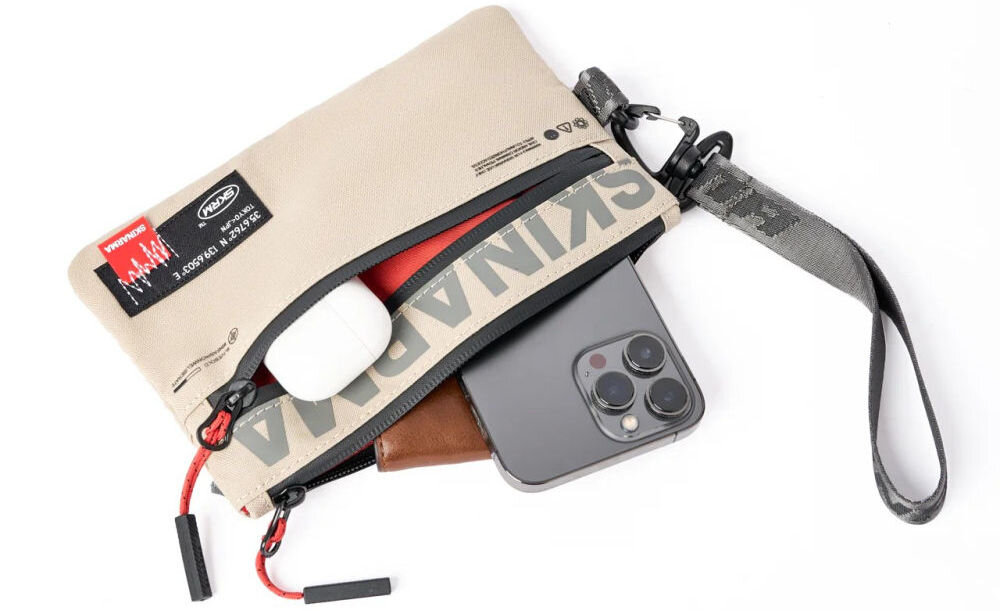 Torebka na telefon SKINARMA Fardel Kość słoniowa prezentacja torebki na białym tle z wystającym telefonem portfelem i słuchawkami z kieszeni wnętrze z kieszeniami i wodoodporny materiał ułatwienie organizacji