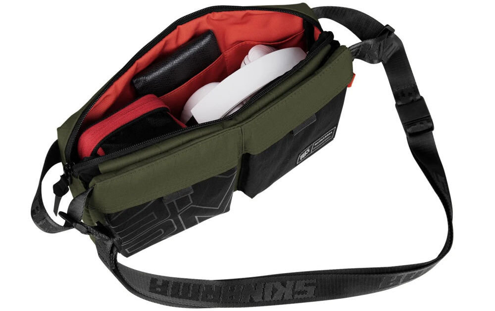 Torebka SKINARMA Crossbody Jager Oliwkowa prezentacja otwartej torby na białym tle kieszenie i regulowany pasek z magnetycznym zapięciem pętle montażowe kieszeń na zamek bezpieczne przechowywanie