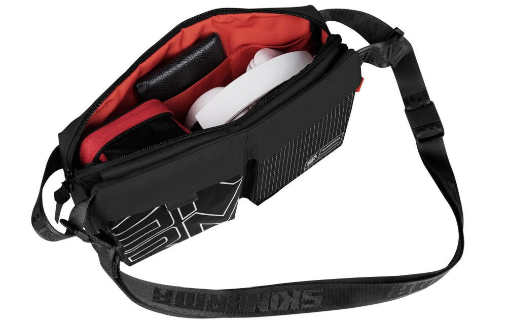 Torebka SKINARMA Crossbody Jager Czarna prezentacja otwartej torby na białym tle kieszenie i regulowany pasek z magnetycznym zapięciem pętle montażowe kieszeń na zamek bezpieczne przechowywanie