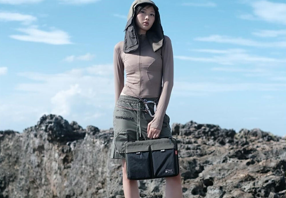 Torba na laptopa SKINARMA Jager 14 cali Oliwkowy prezentacja torby trzymanej w dłoni przez osobę na tle skał i nieba połączenie stylu i technologii