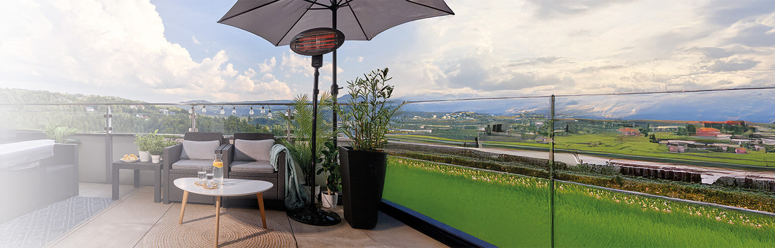 Promiennik podczerwieni - tarasowy MUG-25 n a tarasie, obok kanapa ogrodowa, stolik z lemoniadą, kwiaty w dużych donicach.