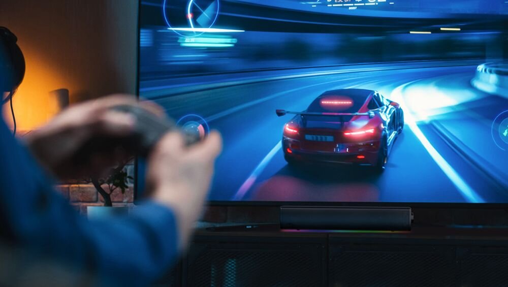 Soundbar komputerowy CREATIVE GS3 2.0 Bluetooth 5.4 A2DP bezprzewodowa transmisja stereo do 10 m, osoba grająca na kosnosli, soundbar stojący pod telewizorem