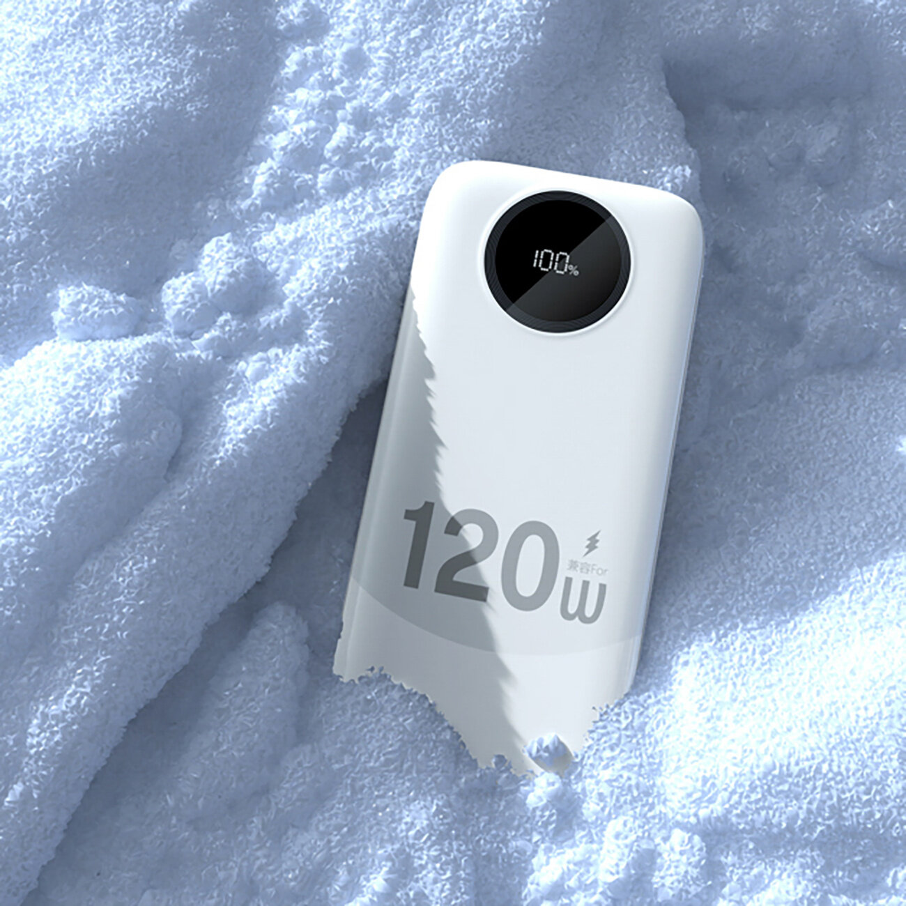 Biały powerbank leży na śniegu, z wyświetlaczem pokazującym \'100%\'. Na obudowie widoczny jest napis \'120W\'.