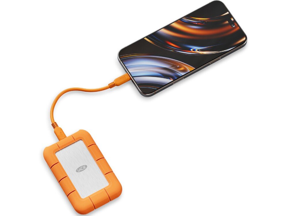 Dysk LACIE Rugged SSD4 Pomarańczowo-srebrny dysk przenośny połączony pomarańczowym przewodem z telefonem, na którego ekranie widoczne są kolorowe refleksy świetlne, kompatybilność, systemy