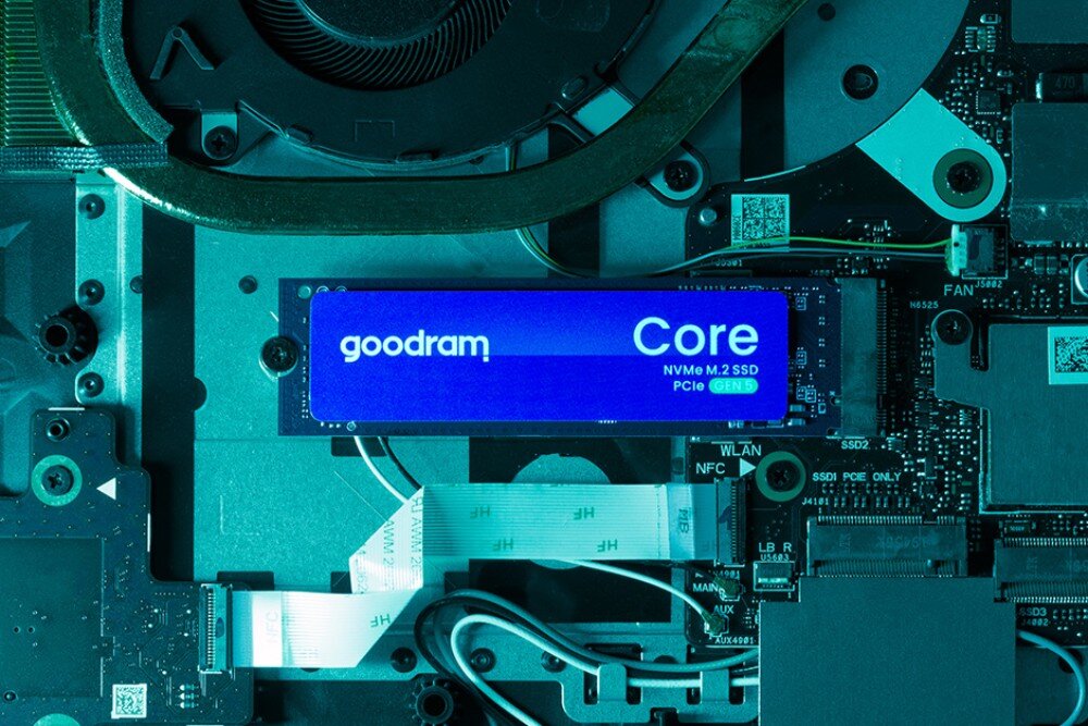 Dysk GOODRAM Core Widok z góry na dysk M.2 z etykietą 'goodram Core NVMe M.2 SSD PCIe GEN 5' zamontowany na zielonkawo oświetlonej płycie głównej komputera obok wentylatora, konstrukcja, kości pamięci, wydajność
