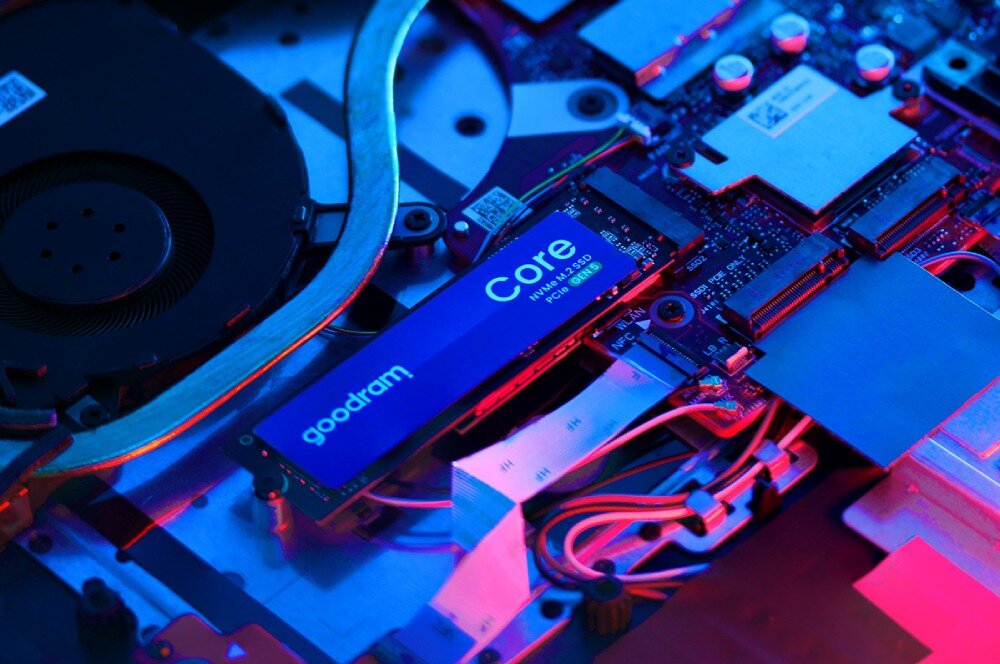 Dysk GOODRAM Core Ukośny widok na dysk M.2 z etykietą 'goodram Core' zamontowany w złączu na płycie głównej komputera, oświetlony kontrastowym niebieskim i czerwonym światłem, żywotność, wytrzymałość