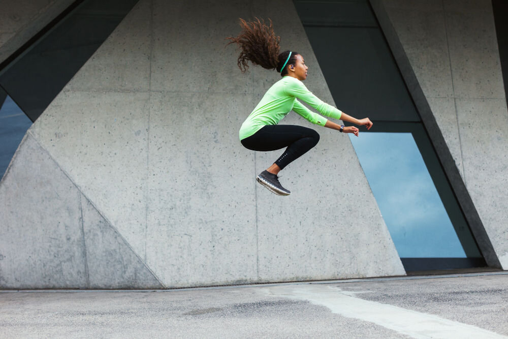 JBL Endurance Zone cztery mikrofony formowanie wiązki redukcja szumów, osoba z założonymi słuchawkami wykonująca skok wzwyż