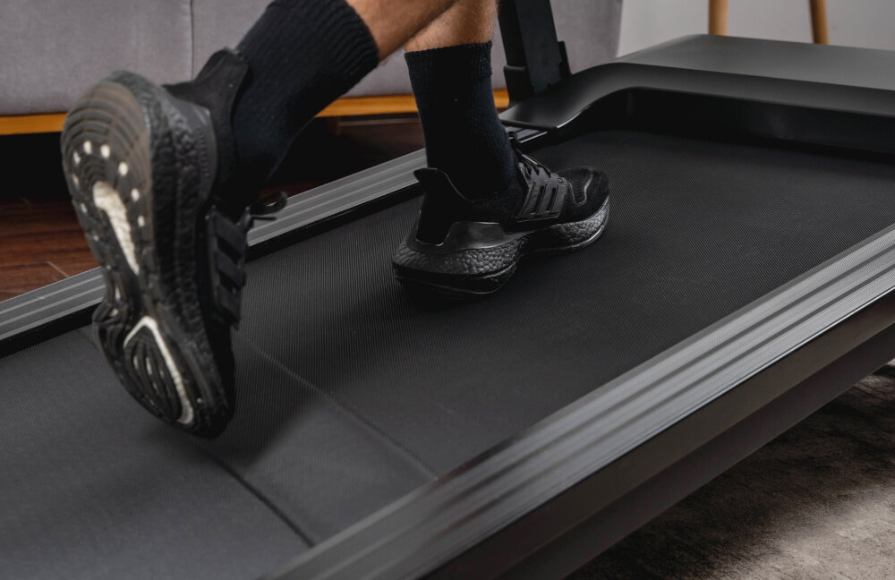 Bieżnia elektryczna KETTLER Track 200 1471W 16 km-h zbliżenie na pas biegowy osoba biegnie na bieżni regulacja prędkości 1-16 km/h w krokach co 0,1 km/h klucz bezpieczeństwa z funkcją automatycznego zatrzymania silnik bezszczotkowy o mocy 2 KM powierzchnia biegowa 130 × 48 cm