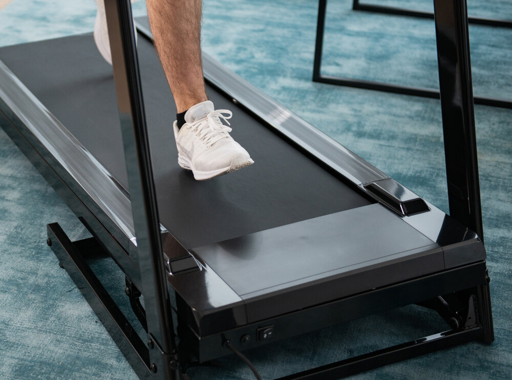 Bieżnia elektryczna KETTLER Track 100 1287W 16 km-h zbliżenie na pas biegowy osoba biegnie na bieżni regulacją prędkości w zakresie 1-16 km/h silnik o mocy 1,75 KM około 1287 W płynna i cicha praca szeroki pas biegowy maksymalna waga użytkownika do 100 kg wbudowana amortyzacja chronią stawy zgodność z normą sprzętu fitness H bieżnia jest odpowiednia do codziennego użytku w domu