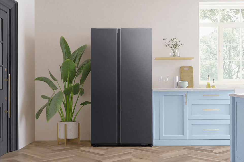 Zdjęcie przedstawia lodówkę z zamrażarką która stoi na początku błękitnej kuchni obok zielonej rośliny w doniczce