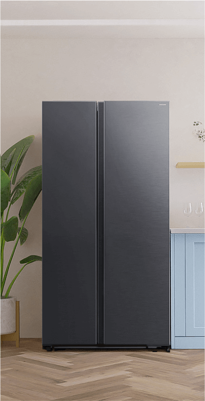 Grafika przedstawia lodówkę z zamrażarką stojąca w kuchni obok zielonej rośliny