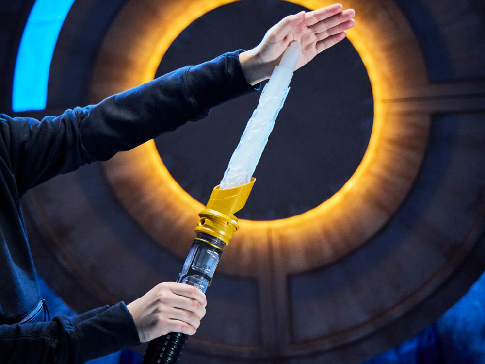 Miecz świetlny HASBRO Star Wars Lightsaber Kyber G07275L0 Dłonie dziecka łączące srebrną rękojeść z fioletowym, półprzezroczystym modułem środkowym miecza świetlnego.