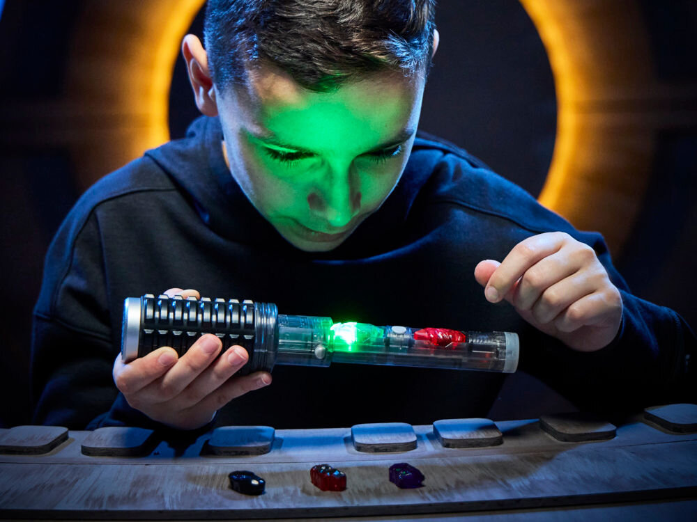 Miecz świetlny HASBRO Star Wars Lightsaber Kyber G07275L0 Dziecko w szarym bezrękawniku trzymające fioletowy miecz świetlny w dynamicznej pozie bojowej, prezentując pełną długość zabawki.