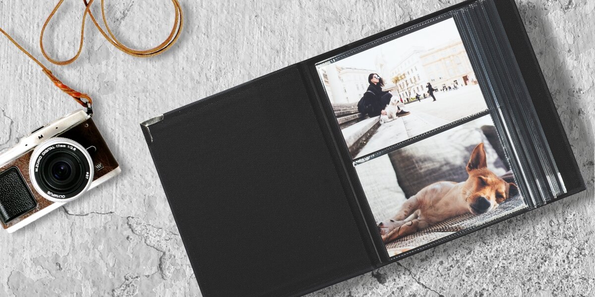 Szybkie porządkowanie zdjęć czarny album na zdjęcia z napisem breathe love dream na okładce, leżący na drewnianym stole obok laptopa, okularów i małej doniczki z sukulentem.