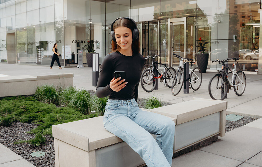 Edifier W820NB Plus V25 ANC -49dB tryby High Medium Ambient Wind Reduction, osoba z założonymi słuchawkami nausznymi w plenerze