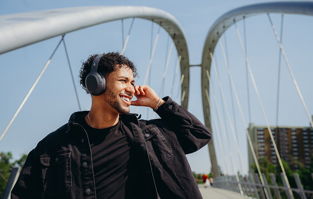 Edifier W820NB Plus V25 mikrofony AI redukcja szumów czysty głos rozmowy telefoniczne wideokonferencje, osoba z założonymi słuchawkami nausznymi w plenerze