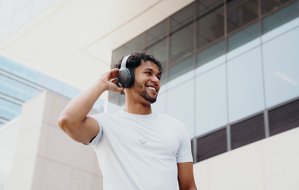 Edifier W820NB Plus V25 bateria 88h szybkie ładowanie 15min 15h ANC, osoba z założonymi słuchawkami nausznymi w pomieszczeniu