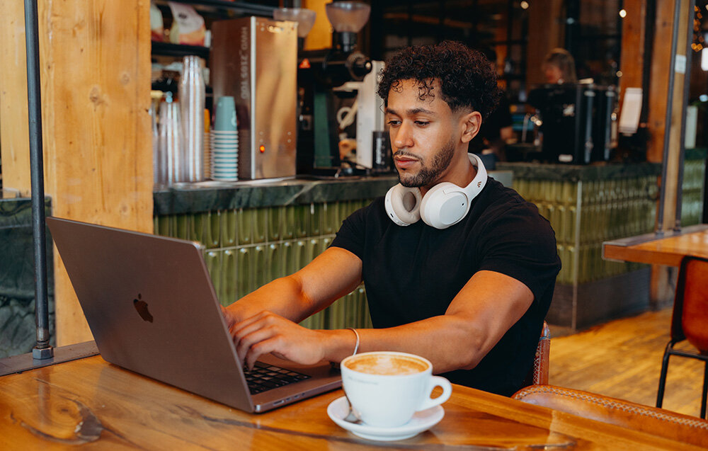 Słuchawki Edifier W820NB Plus V25 bezprzewodowe ANC LDAC Bluetooth 6.1 komfortowe nauszne, osoba siedząca przed laptopem