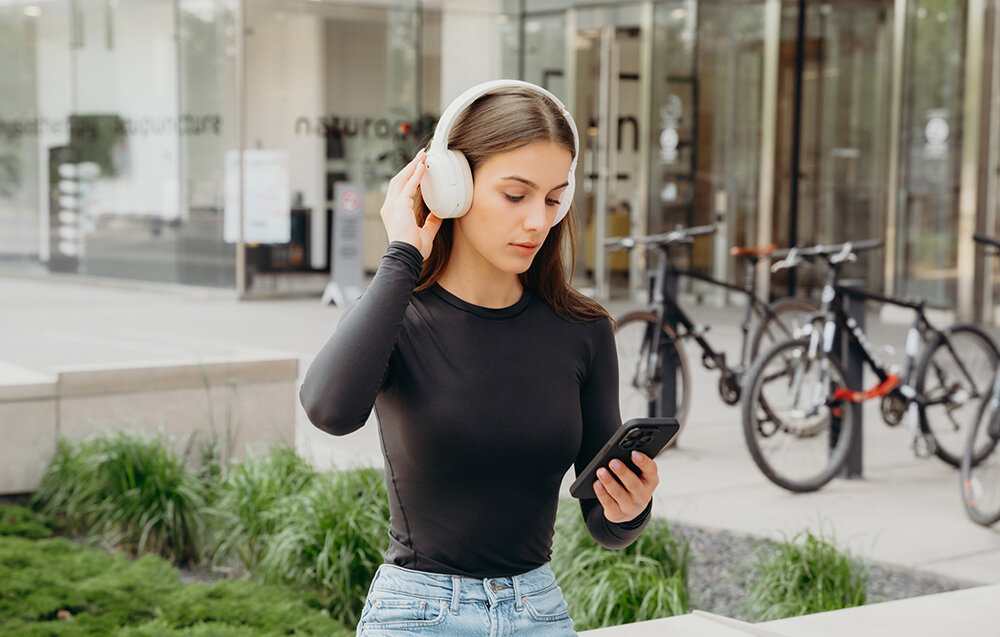 Edifier W820NB Plus V25 ANC -49dB tryby High Medium Ambient Wind Reduction, osoba z założonymi słuchawkami nausznymi w plenerze