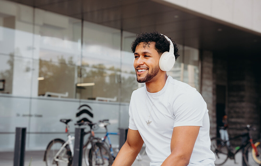 Edifier W820NB Plus V25 Bluetooth 6.1 Multipoint tryb Gaming niskie opóźnienie, osoba z założonymi słuchawkami nausznymi w plenerze